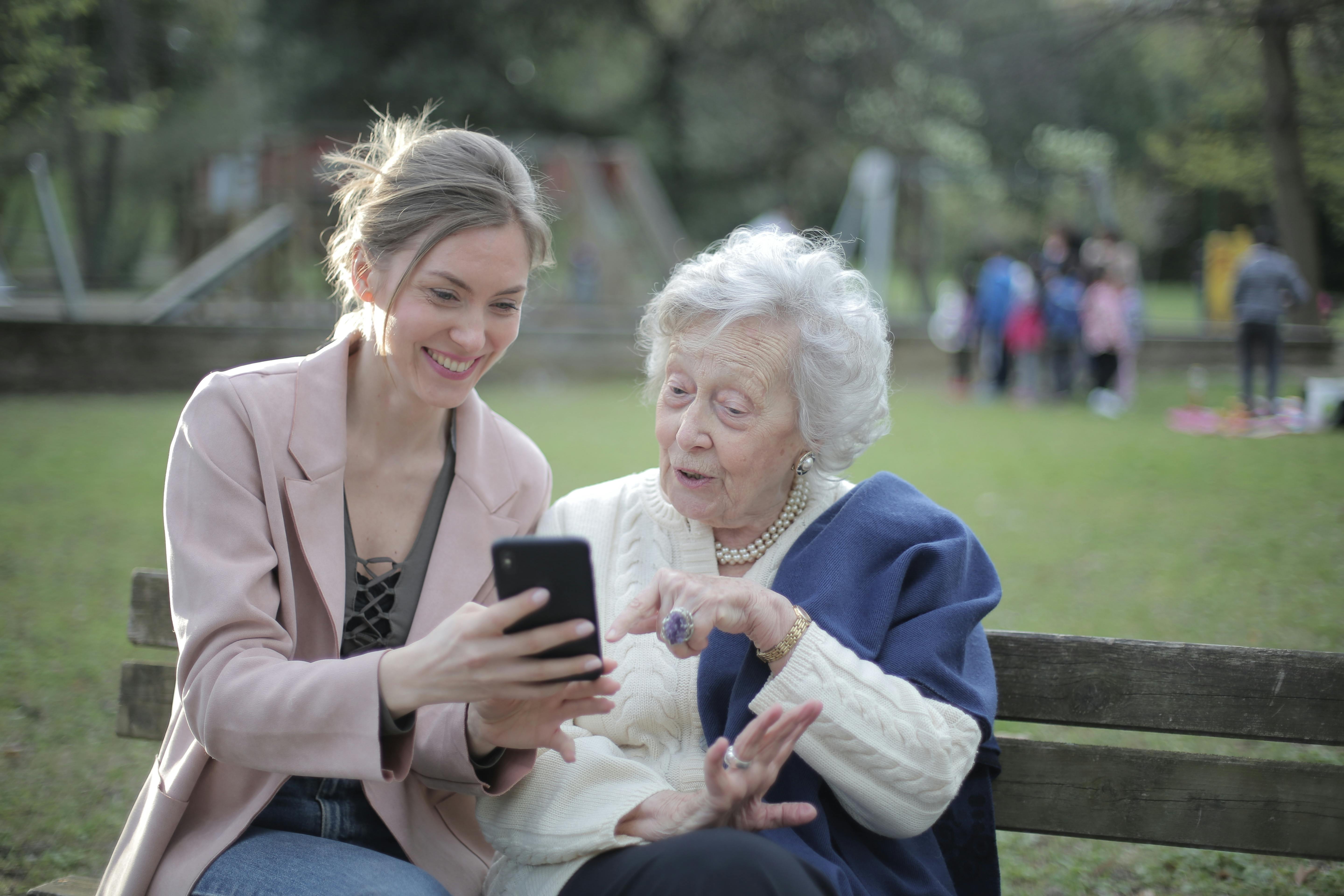 Grand-mère souriante avec sa petite-fille regardant un téléphone